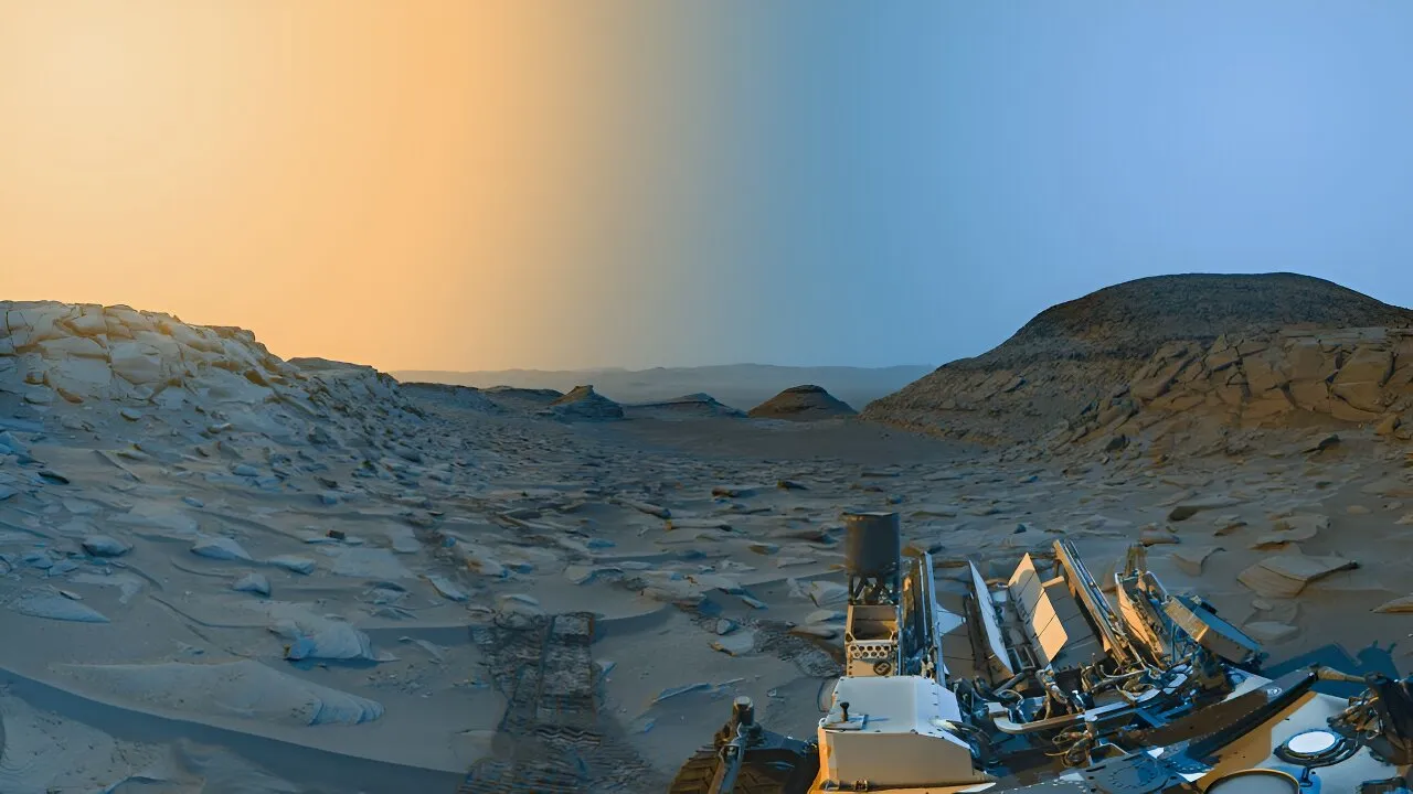 这张全景图是由好奇号于2023年4月8日拍摄的火星盖尔陨石坑标记带谷（Marker Band Valley）的两张照片合并而成，分别是在当地时间的上午和下午。原始图像是黑白拍摄的，然后进行了着色，右边部分（蓝色天空）代表上午的场景，左边部分（黄色天空）代表下午的场景。This panorama was merged from two images of “Marker Band Valley” in Mars’s Gale crater taken by Curiosity on 8 April 2023, one in the morning and one in the afternoon local time. The original images were taken in black and white and then colorized, with the right portion (under blue sky) representing the scene in the morning and the left portion (under yellow sky) representing the afternoon. Credit: NASA/JPL-Caltech